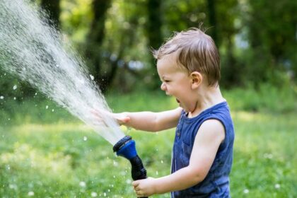 child enjoying water from a hose