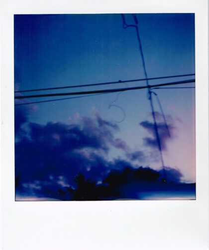 blue clouds in a blue sky caught in the crosshairs of utility wires