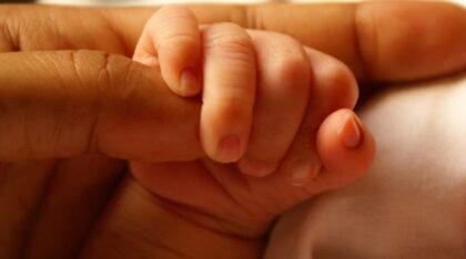 Baby hand holding an adult finger