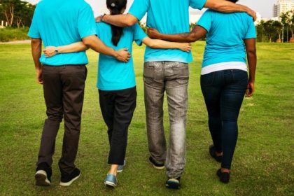 four people walking with their arms around each other