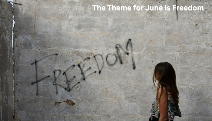 A girls stands reading a scrawl on a wall that says "Freedom."