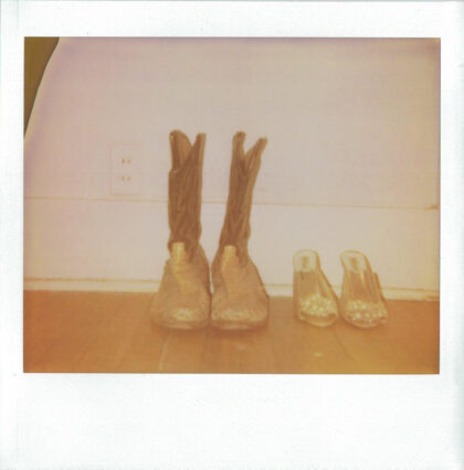 Cowboy boots and slippers lined up against a wall.