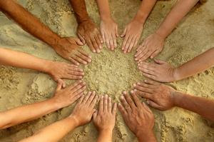 circle of hands above the sand