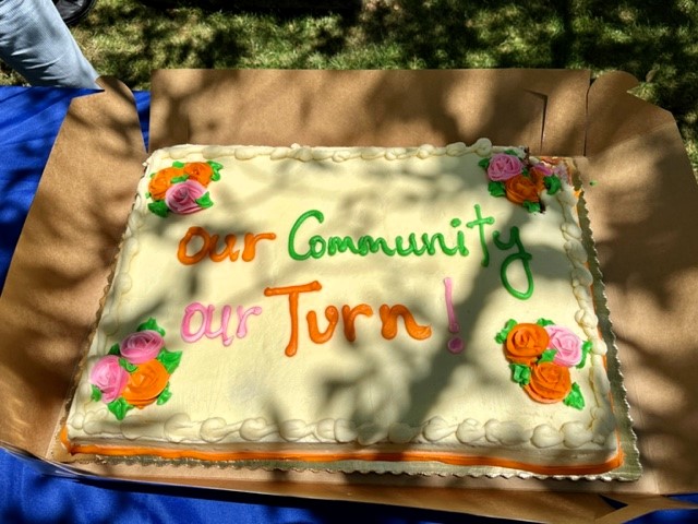 Square cake says "Our Community Our Turn."